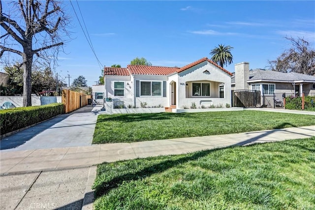 mediterranean / spanish house with a front yard, a tile roof, fence, and stucco siding