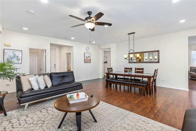 living area with baseboards, ceiling fan with notable chandelier, dark wood finished floors, and recessed lighting