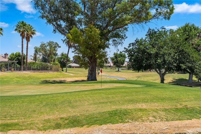 view of home's community with a yard, golf course view, and fence