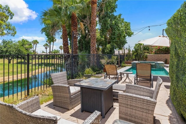 view of patio with an outdoor fire pit, a water view, a fenced backyard, and a pool with connected hot tub