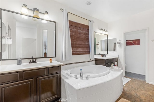 bathroom with a garden tub, two vanities, and a sink