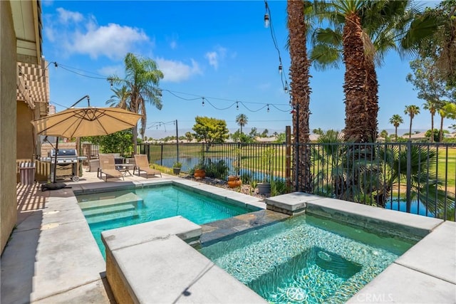 view of swimming pool featuring a pool with connected hot tub, a water view, fence, and grilling area