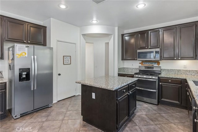 kitchen with stainless steel appliances, a center island, light stone countertops, and recessed lighting