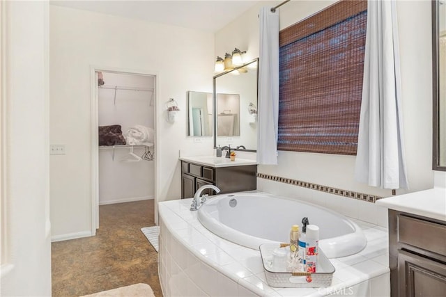 bathroom featuring a garden tub, a spacious closet, and vanity