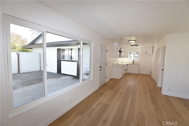 entryway with baseboards, a sink, and light wood-style floors