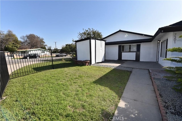 view of yard with a shed, fence, a patio, and an outbuilding