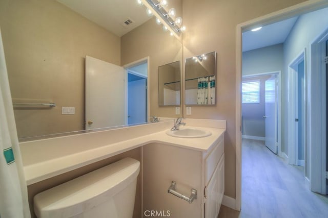 bathroom featuring visible vents, vanity, toilet, and baseboards