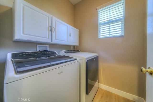 laundry area featuring washing machine and dryer, cabinet space, light wood-style flooring, and baseboards