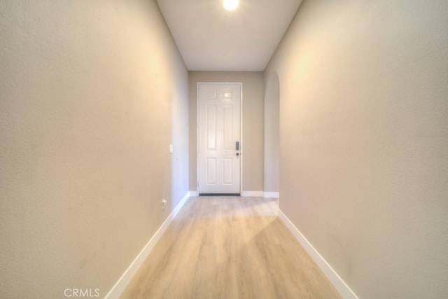 corridor featuring light wood finished floors and baseboards