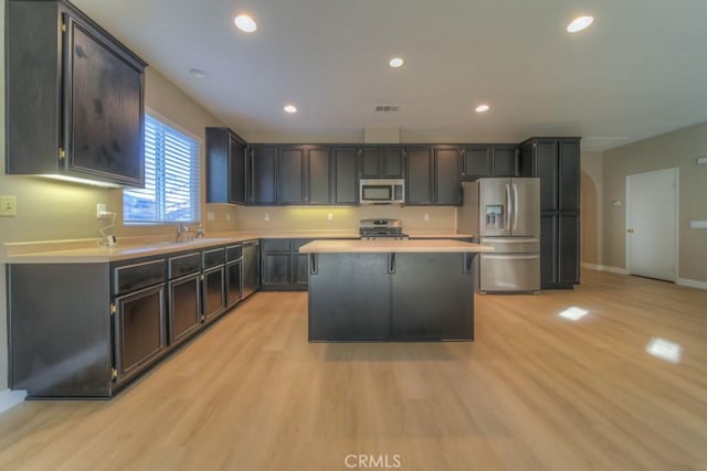 kitchen with light wood-style floors, stainless steel appliances, light countertops, and a center island