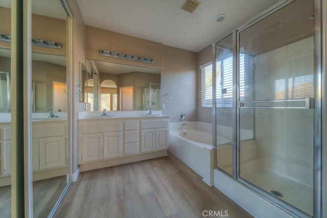 full bath featuring visible vents, a sink, a garden tub, and wood finished floors