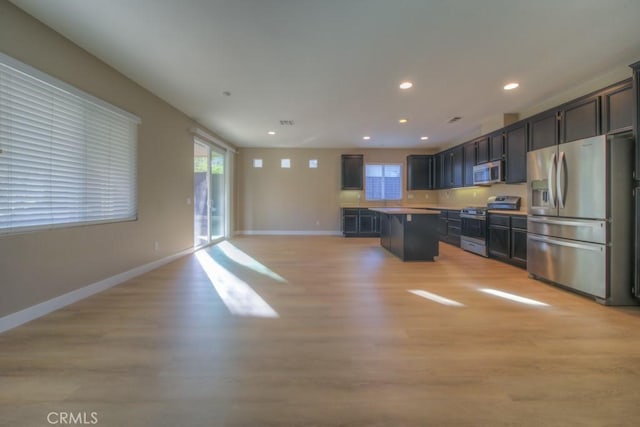 kitchen with a breakfast bar area, light wood-style floors, open floor plan, appliances with stainless steel finishes, and a center island