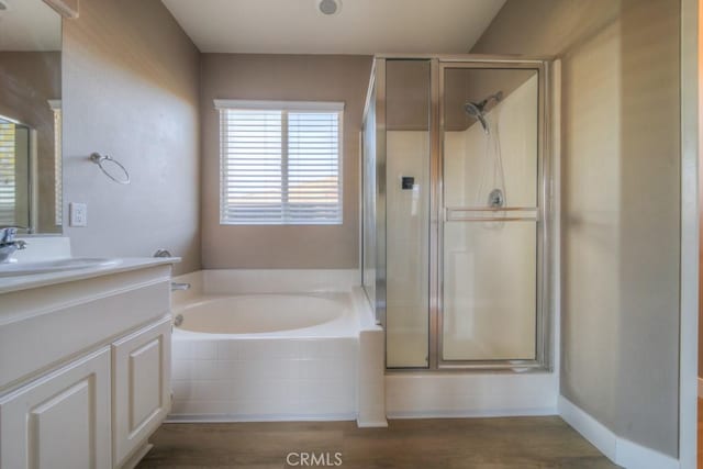 bathroom with baseboards, wood finished floors, vanity, a shower stall, and a bath