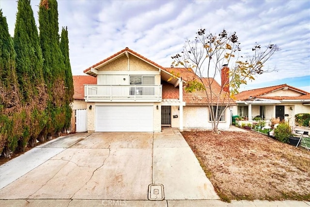 view of front of house with a garage, concrete driveway, a balcony, and stucco siding