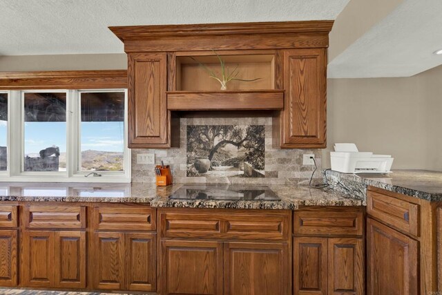 29345 Wilkes Rd, Valley Center, CA 92082 - kitchen with black electric stovetop, dark stone counters, brown cabinets, and a textured ceiling