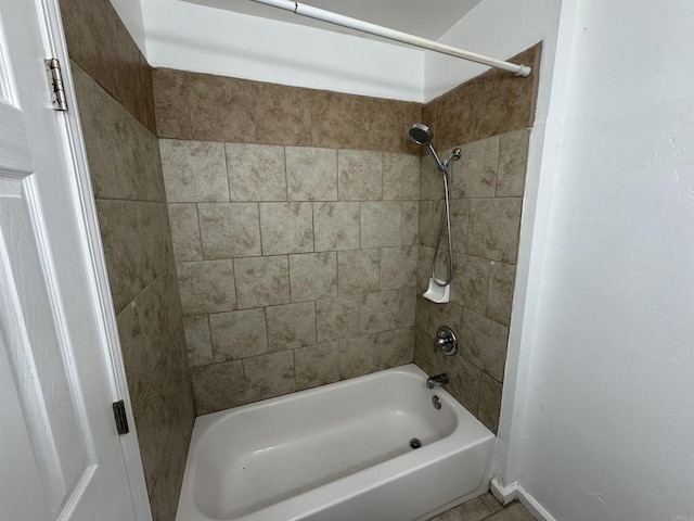 bathroom featuring baseboards and bathing tub / shower combination