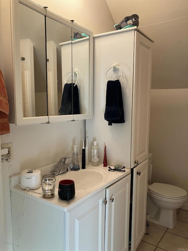 bathroom with toilet, vanity, and tile patterned floors