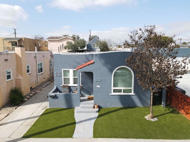 view of front of property featuring fence, a front lawn, and stucco siding