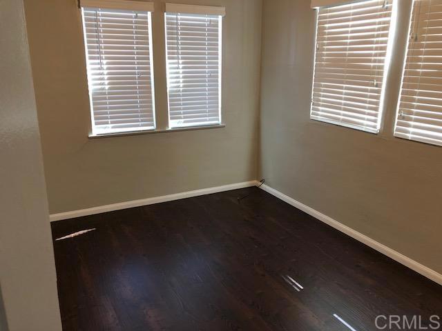 unfurnished room with a wealth of natural light, baseboards, and wood finished floors