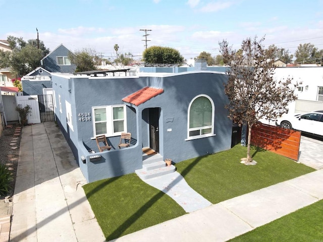 view of front facade with a front lawn, fence, a gate, and stucco siding