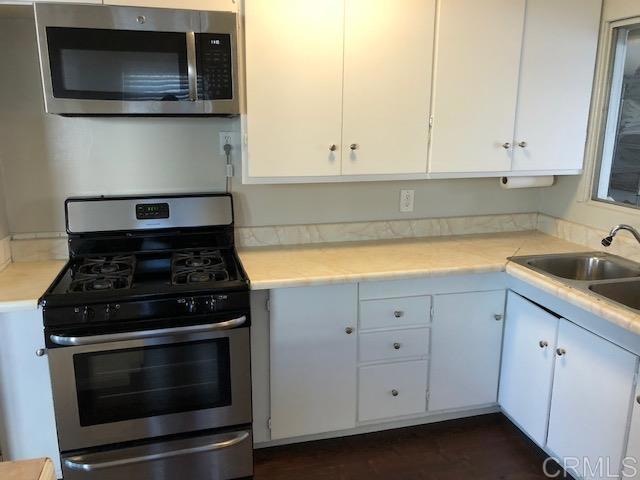 kitchen featuring stainless steel appliances, light countertops, white cabinets, and a sink