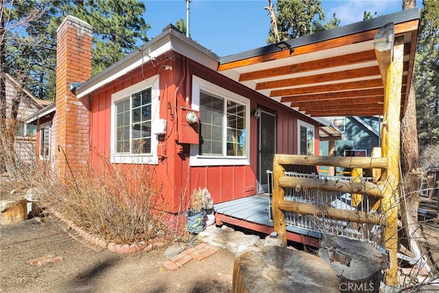 view of home's exterior with a deck, board and batten siding, and a chimney