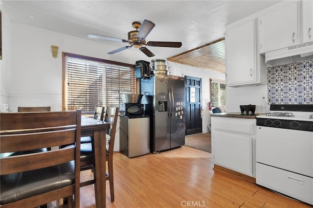 kitchen with stainless steel refrigerator with ice dispenser, white gas range, white cabinetry, light wood-type flooring, and under cabinet range hood