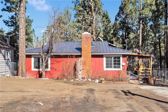 view of front of house with a standing seam roof, a chimney, and metal roof