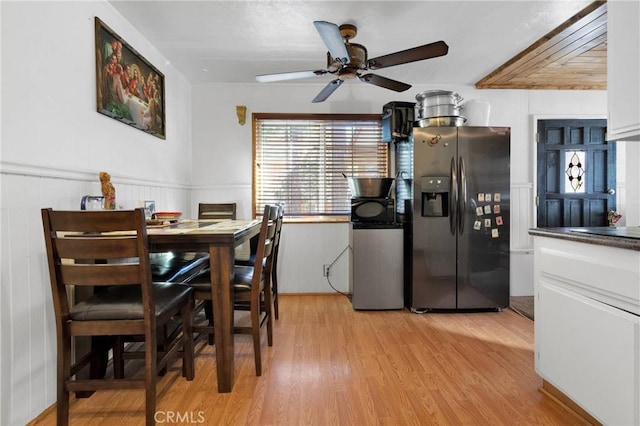 dining room featuring a ceiling fan, light wood-type flooring, and wainscoting