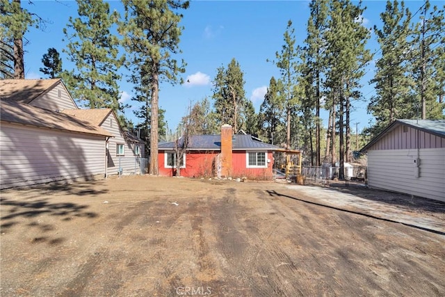 back of property featuring driveway, a chimney, and fence