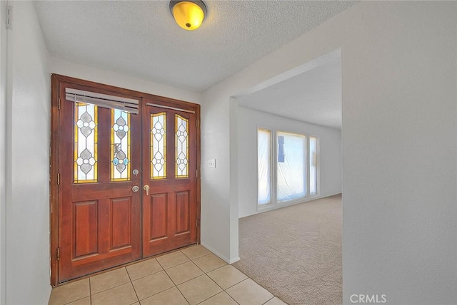 foyer with light carpet, light tile patterned floors, and a textured ceiling