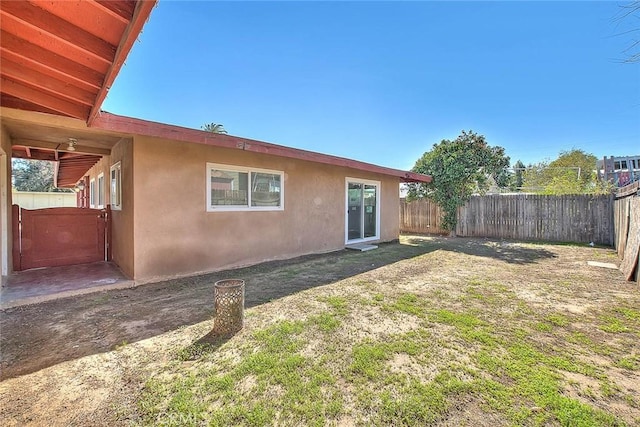 rear view of property featuring fence, a lawn, and stucco siding