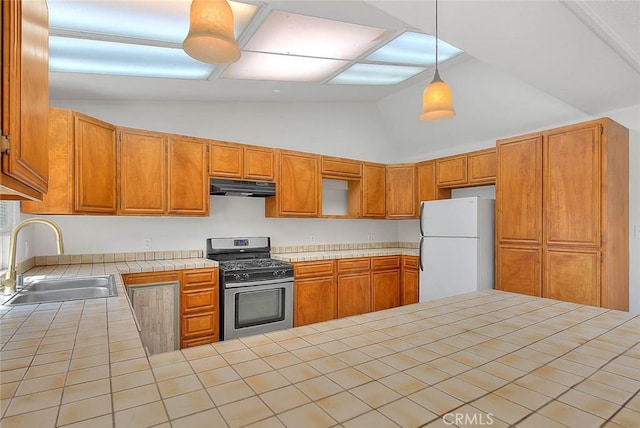 kitchen with tile countertops, gas range, freestanding refrigerator, decorative light fixtures, and under cabinet range hood