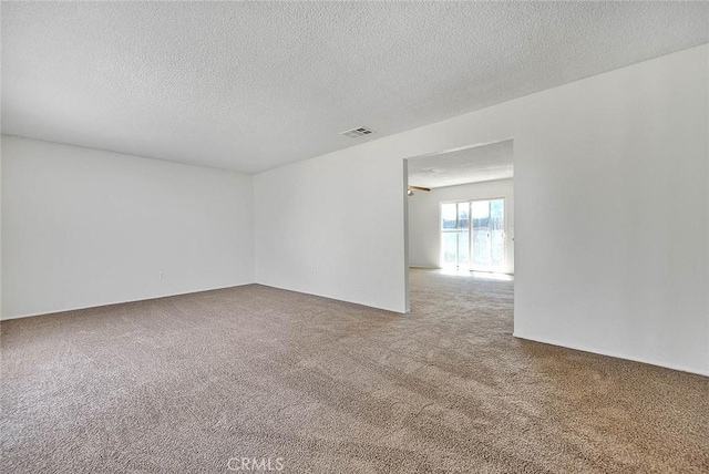 carpeted spare room featuring visible vents and a textured ceiling