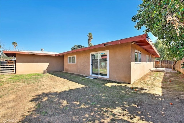 rear view of house with fence and stucco siding