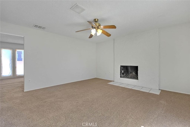 unfurnished living room featuring visible vents, light colored carpet, a fireplace with flush hearth, ceiling fan, and a textured ceiling