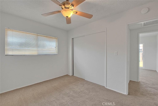 unfurnished bedroom featuring a closet, light colored carpet, visible vents, and multiple windows