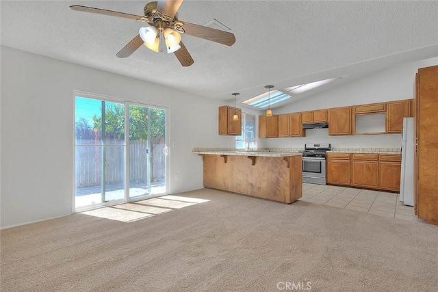 kitchen with light colored carpet, light countertops, stainless steel range oven, a peninsula, and a kitchen bar