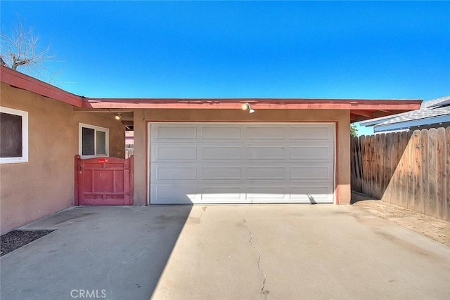 garage featuring driveway and fence