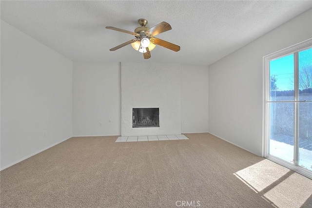 unfurnished living room featuring a textured ceiling, ceiling fan, a fireplace, and light colored carpet