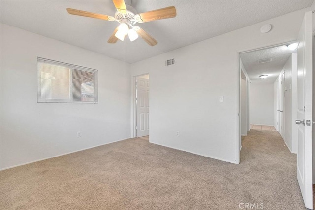 empty room with light carpet, visible vents, and a textured ceiling