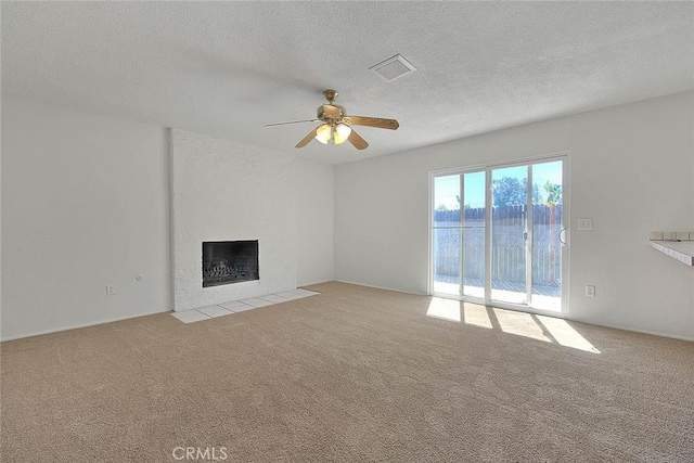 unfurnished living room featuring light carpet, a textured ceiling, a fireplace, and visible vents