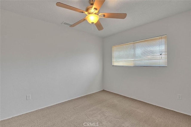 carpeted spare room with visible vents and a ceiling fan