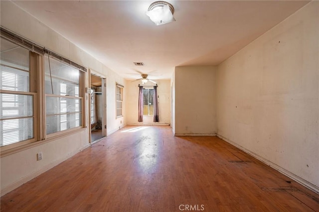 empty room featuring ceiling fan, wood finished floors, visible vents, and baseboards