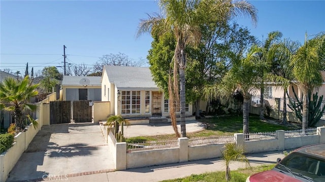 view of front of house with a fenced front yard, a gate, driveway, and stucco siding