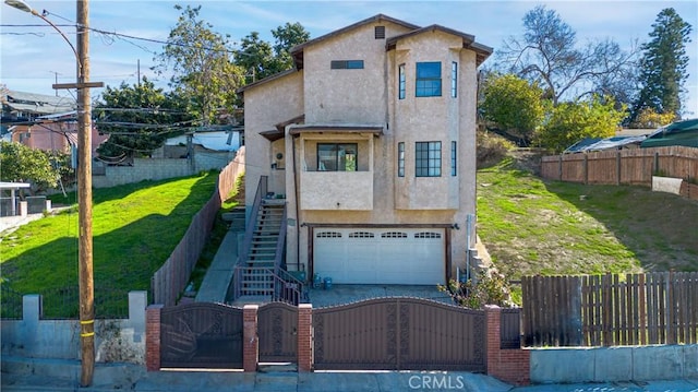 view of front of property with a fenced front yard, driveway, stairway, a gate, and stucco siding