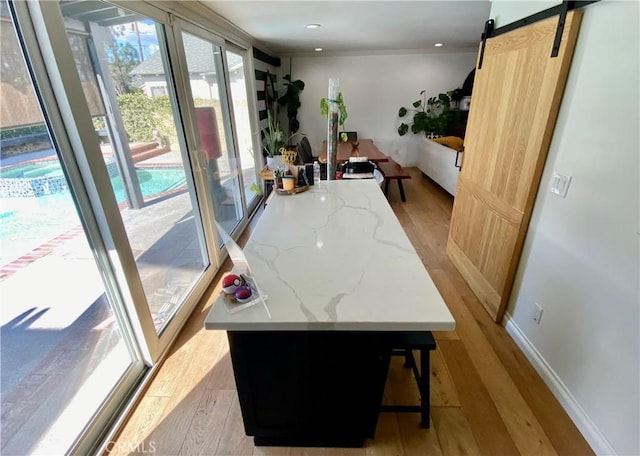 interior space with baseboards, a barn door, recessed lighting, and light wood-style floors