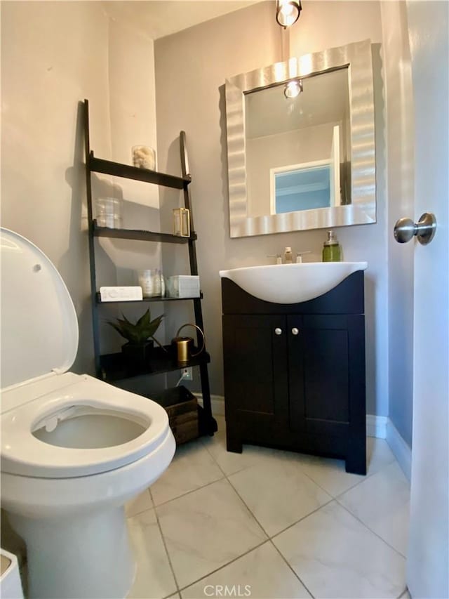 bathroom featuring toilet, baseboards, and vanity