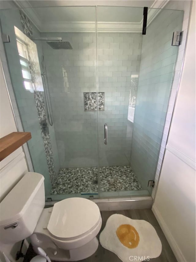 bathroom featuring a stall shower, toilet, and crown molding