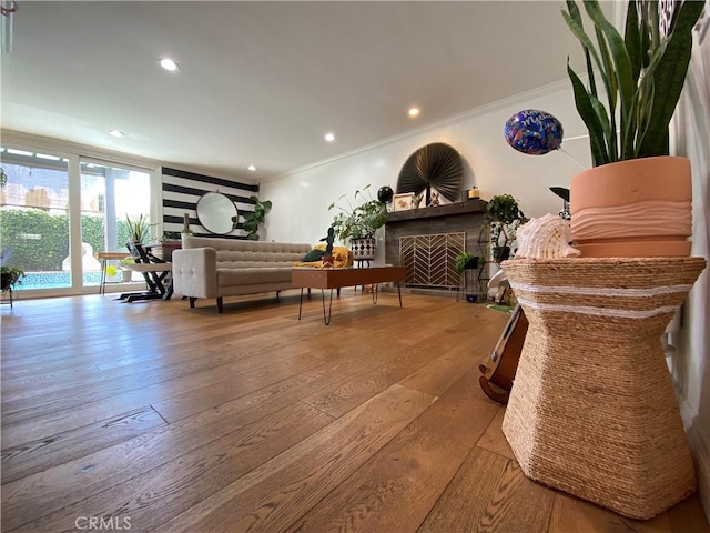 interior space with light wood finished floors, a fireplace, crown molding, and recessed lighting